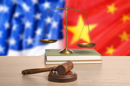 Judge's gavel, scales of justice and books on wooden table against flags of USA and Chinaの写真素材
