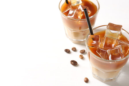 Tasty iced coffee and beans on white table, closeup. Space for text