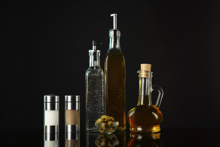 Salad dressings, spices and olives on mirror surface against black backgroundの写真素材