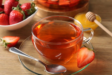 Aromatic fruit tea with strawberries and honey on wooden table, closeupの写真素材