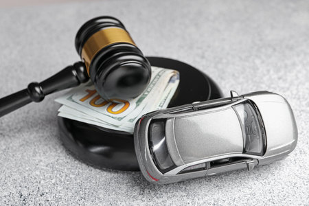 Motor vehicle accident law. Gavel, money and car model on grey background, closeupの写真素材