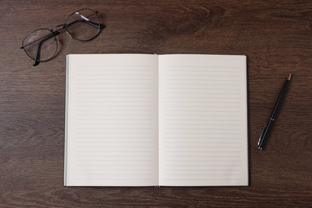 Open blank notebook, pen and glasses on wooden table, flat lay