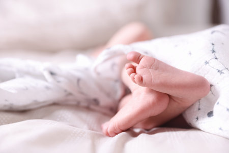 Little baby lying on bed indoors, closeup. Space for text
