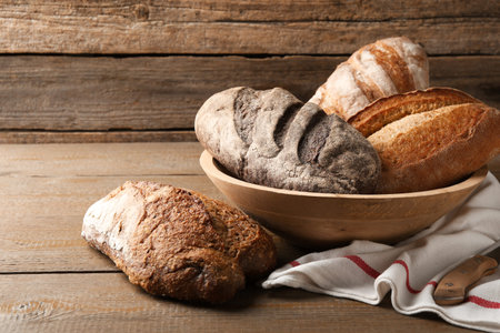Different loaves of fresh bread and knife on wooden table