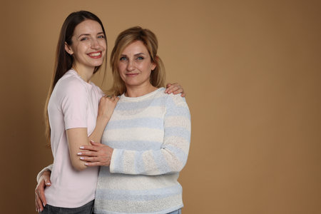 Portrait of mother and daughter on beige background. Space for textの写真素材