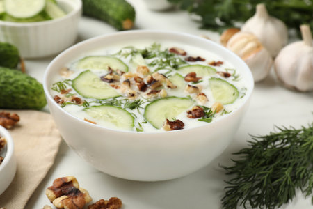 Tasty cucumber soup with dill and nuts in bowl on white table, closeupの写真素材