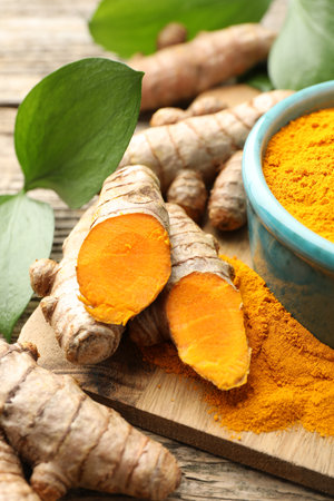 Turmeric powder, roots and leaves on wooden table, closeupの写真素材