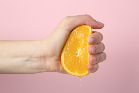 Woman squeezing orange on pink background, closeupの写真素材