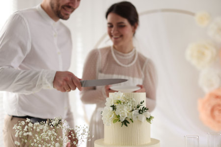 Married couple cutting delicious wedding cake with knife indoors, selective focusの写真素材