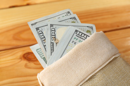 Money bag with dollar banknotes on wooden table, closeupの写真素材