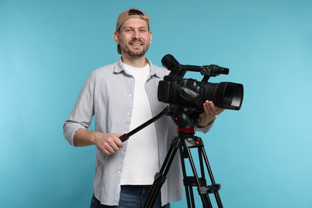 Man with professional video camera on light blue backgroundの写真素材