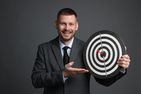 Targeting. Man with dart board and arrow on grey backgroundの写真素材