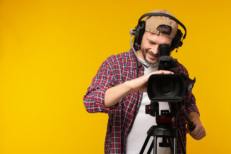 Man with professional video camera and headset on orange backgroundの写真素材