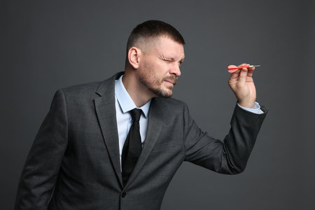 Targeting. Man with dart aiming on grey backgroundの写真素材