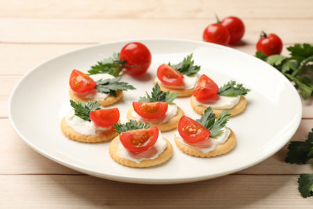 Tasty crackers with cream cheese, tomatoes and parsley on white wooden table, closeupの写真素材