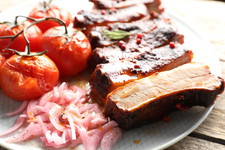 Delicious pork ribs, sun dried tomatoes and onion on wooden table, closeupの写真素材