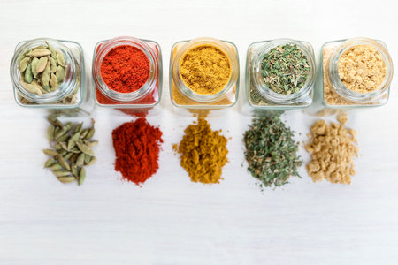 Different aromatic spices in jars on white table, flat layの写真素材