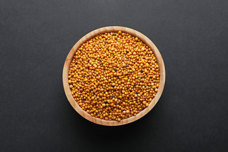 Aromatic mustard seeds in bowl on dark table, top viewの写真素材