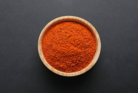 Aromatic paprika powder in bowl on dark table, top viewの写真素材