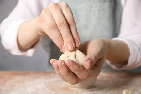 Woman making khinkali on table in kitchen, closeupの写真素材