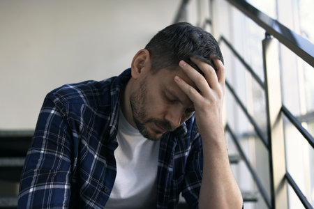Depressed man sitting on stairs in buildingの写真素材