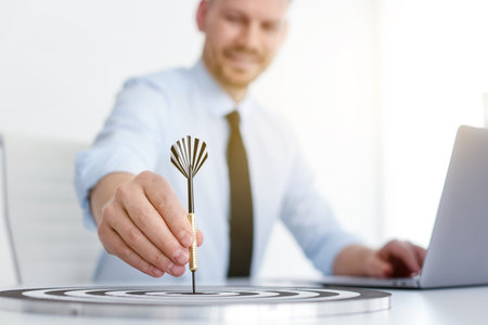 Man with dart aiming at dartboard while working indoors, selective focusの写真素材