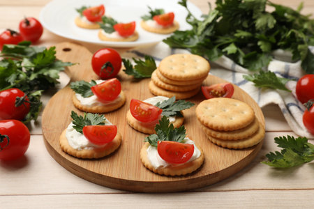 Tasty crackers with cream cheese, tomatoes and parsley on white wooden table, closeupの写真素材