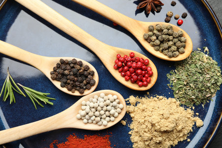 Different aromatic spices in spoons on plate, closeup