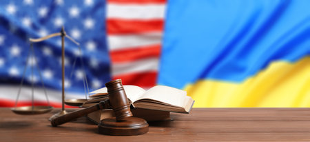 Judge's gavel, scales of justice and books on wooden table against flags of USA and Ukraine. Banner designの写真素材