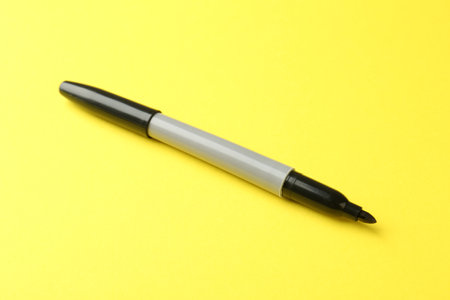 One black marker on yellow background, closeupの写真素材