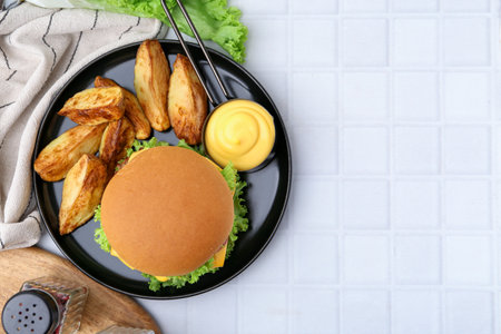 Tasty cheeseburger with sauce and potato wedges on white tiled table, flat lay. Space for textの写真素材