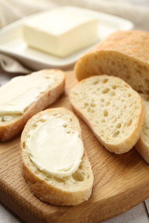 Pieces of bread with butter on light tiled table, closeupの写真素材