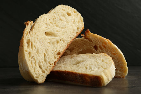 Slices of fresh bread on dark textured table against black background, closeupの写真素材