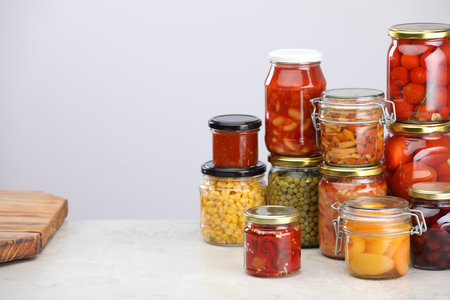 Many jars with different pickled products on light grey table, space for textの写真素材