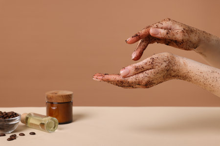Woman applying body scrub onto her hand against dark beige background, closeupの写真素材