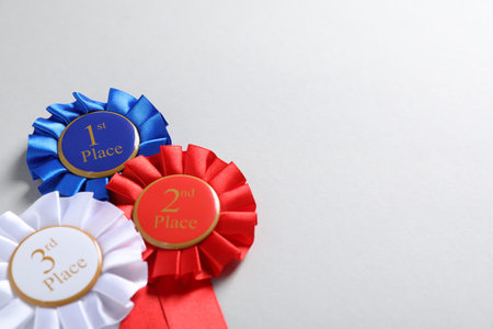 Colorful award ribbons on light gray background, above view. Space for text