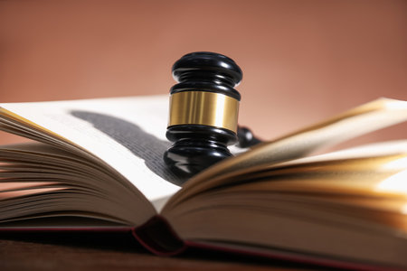 Judge's gavel and open book on table against pale brown background, closeupの写真素材