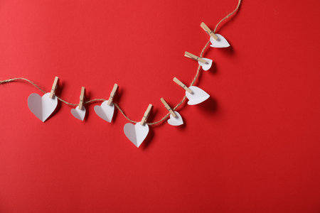 Many paper hearts hanging on rope against red background, flat lay. Space for textの写真素材