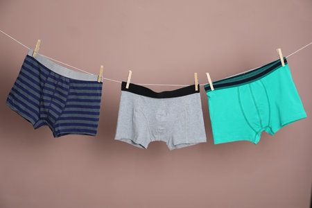 Comfortable men's underwear on clothes line against light brown backgroundの写真素材