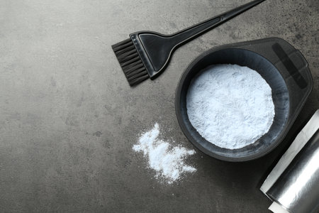 Bowl with hair bleaching powder, foil and brush on gray table, flat lay. Space for textの写真素材