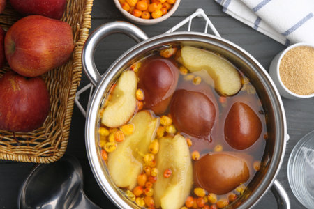 Tasty compot of apples and sea buckthorn berries in pot on grey wooden table, flat layの写真素材