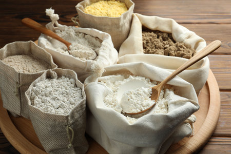 Different types of flour in bags on wooden table, closeupの写真素材