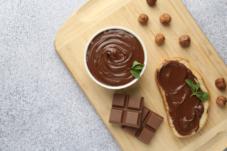 Tasty chocolate spread, toast, hazelnuts and mint on gray textured table, top view. Space for textの写真素材