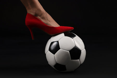 Woman in high heeled shoe with soccer ball on dark background, closeupの写真素材