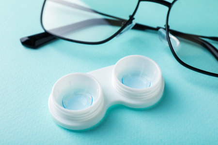Contact lenses in case and glasses on turquoise background, closeupの写真素材