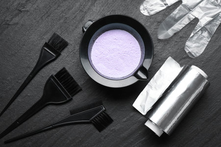 Bleaching powder and hairdresser's tools on black table, flat layの写真素材