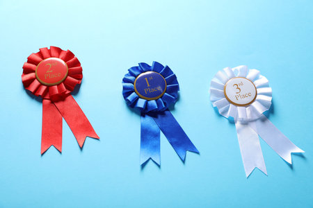 Colorful award ribbons on light blue background, above view