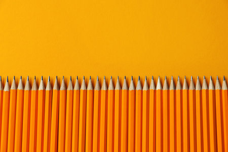 Many pencils on orange background, flat lay. Space for textの写真素材