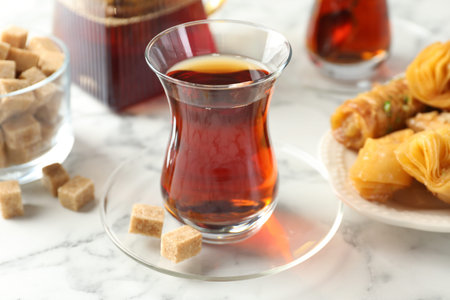 Tasty Turkish tea served with sweets on white marble table, closeup