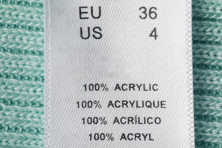 Clothing label with size and material content on garment, top view
